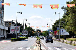 The sun and wind tear the flags on the streets of Podgorica