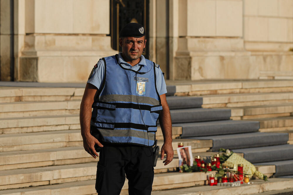 Policajac ispred Ministarstva unutrašnjih poslova Rumunije ispred kojeg su ostavljeni cvijeće i svijeće u znak sjećanja na ubijenu djevojku, Foto: BETA/AP