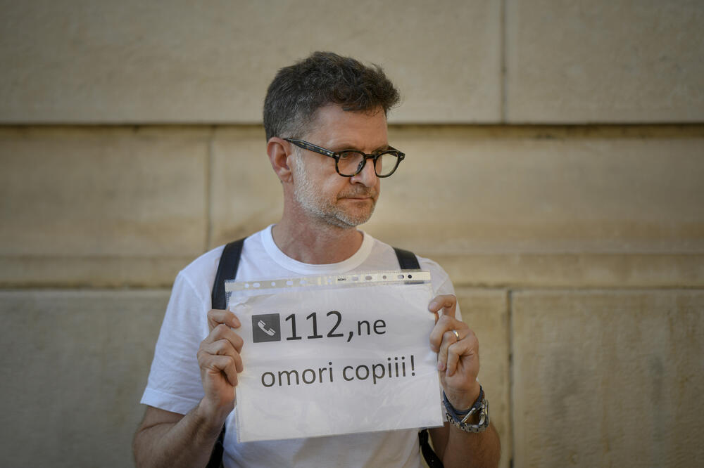 Muškarac drži papir sa porukom "112, ubijate našu djecu", Foto: Andreea Alexandru/AP