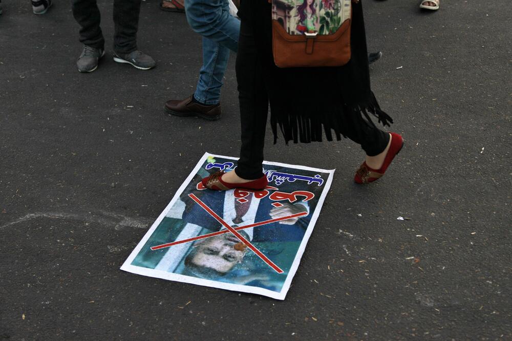Demonstrant gazi poster sa likom Asada al Ejdanija, Foto: Asada al Ejdanija