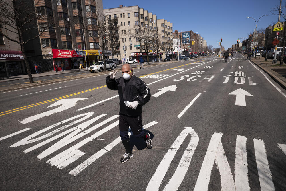 Čovjek džogira pustim ulicama sa maskom i rukavicama: SAD koronavirus, Foto: AP