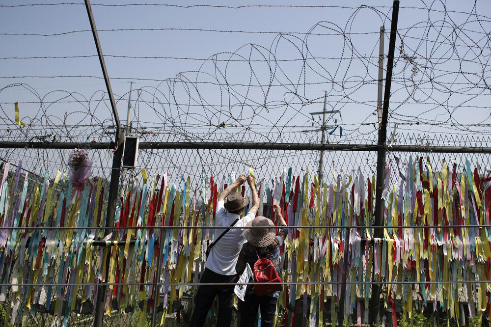 Posjetitelji gledaju na žičanu ogradu ukrašenu vrpcama ispisanu porukama želeći ponovno ujedinjenje dviju Koreja, Foto: Lee Jin-man/AP