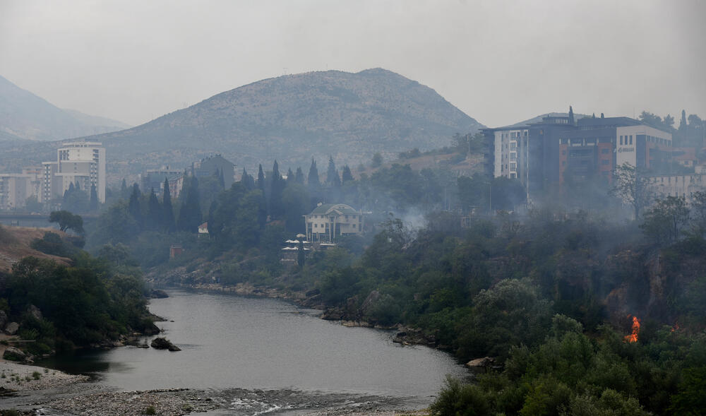 <p>Podgorički vatrogasci gase vatru koja je zahvatila travu, nisko rastinje i drveće i u blizini centra pored mosta Milenijuma</p>