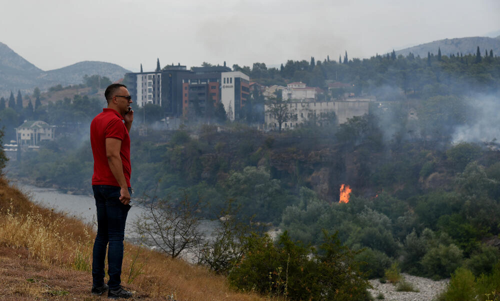 <p>Podgorički vatrogasci gase vatru koja je zahvatila travu, nisko rastinje i drveće i u blizini centra pored mosta Milenijuma</p>