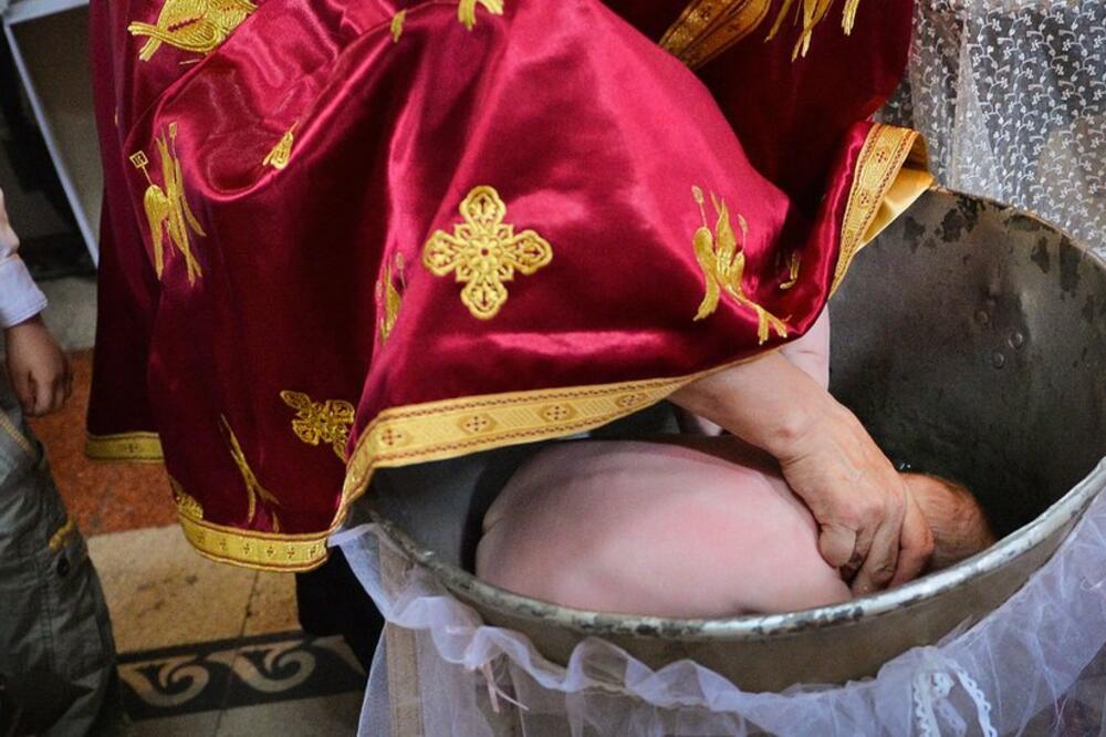 Pravoslavni sveštenici u Rumuniji potapaju glavu deci na krštenju (arhivska fotografija), Foto: AFP