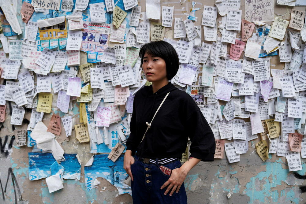 Novinarka Džejd Čang pozira ispred zida sa naljepnicama u četvrti Kvun Tong u Hong Kongu