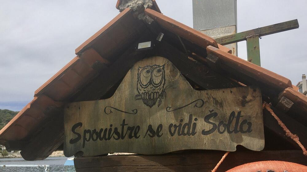 <p>Nenašminkane kuće od kamena, stare masline i smokve, makija. More miluje stijene. Zimzeleno rastinje, izraslo na vjetru, nadnijelo se nad kristalnobistru vodu. Jedan se čovjek zabavio čišćenjem svoje barke u luci</p>