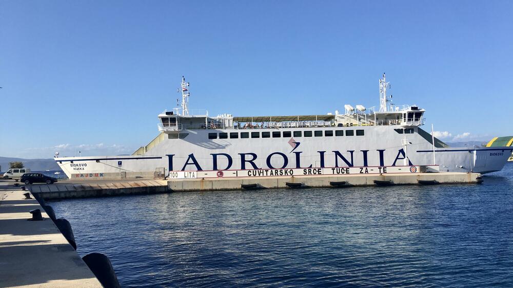 <p>Nenašminkane kuće od kamena, stare masline i smokve, makija. More miluje stijene. Zimzeleno rastinje, izraslo na vjetru, nadnijelo se nad kristalnobistru vodu. Jedan se čovjek zabavio čišćenjem svoje barke u luci</p>