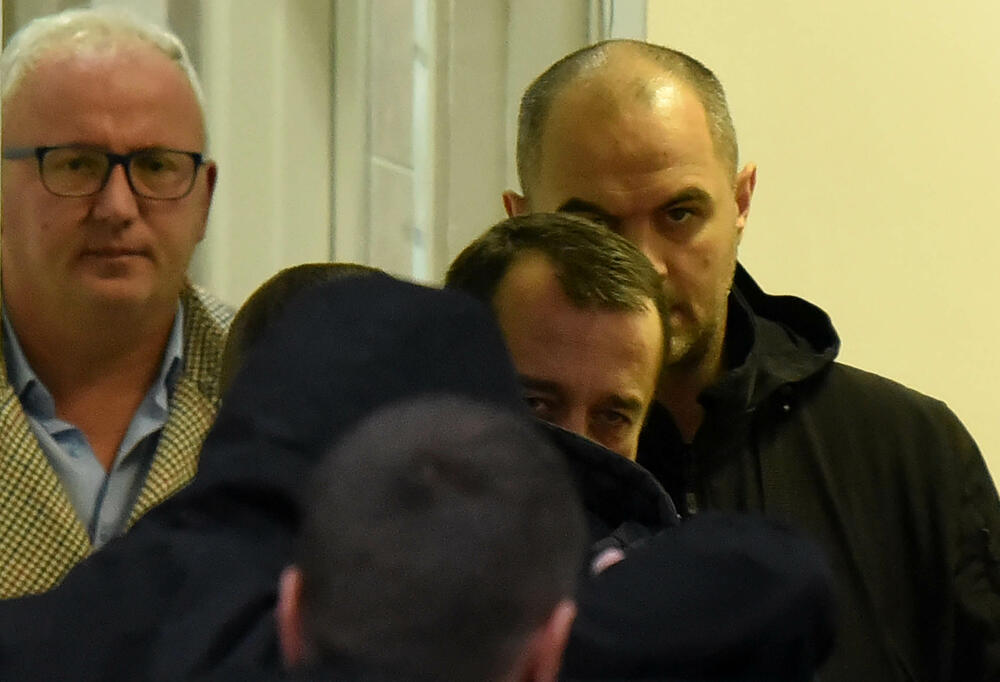 Lazar Aković gleda dok privode njegovog branjenika Sašu Čađenovića 