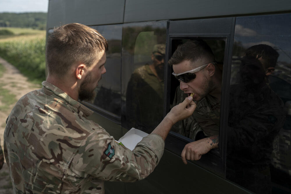 Ukrajinski dobrovoljac hrani kolegu pomfritom nakon obuke na periferiji Kijeva