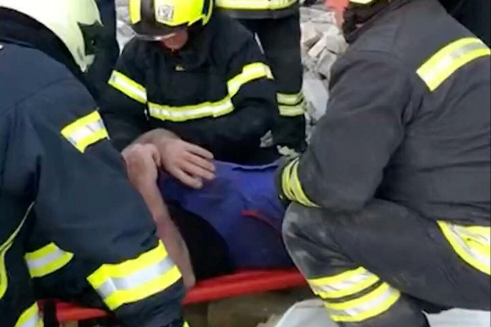 Ukrajinski spasioci pomažu muškarcu na nosilima nakon što je izvučen ispod ruševina, Foto: Reuters