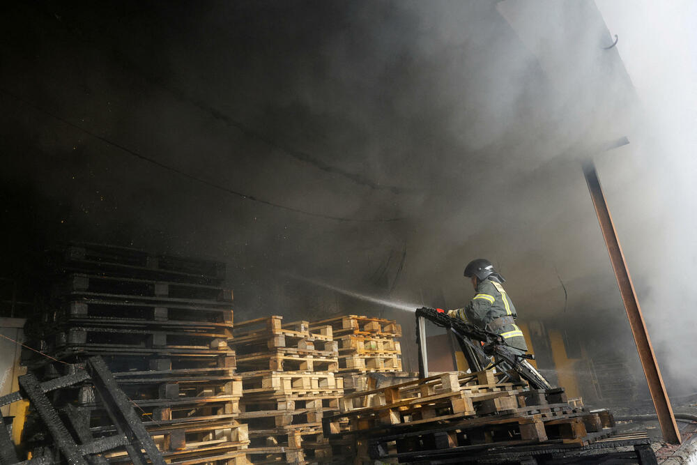 Vatrogasac pokušava da ugasi požar u skladištu u Donjecku pogođenom u ruskom napadu