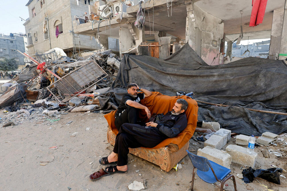 Palestinci ispred uništene zgrade u Kan Junisu, Foto: Rojters