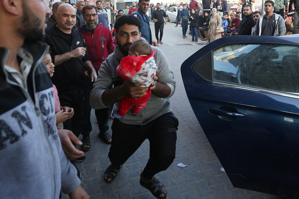 A Palestinian carries an injured baby to a hospital in Khan Younis, Photo: Reuters