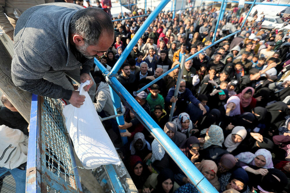 Palestinci dobijaju vreće brašna koje dijeli UNRVA tokom privremenog primirja između Hamasa i Izraela, u Kan Junisu, Foto: Reuters