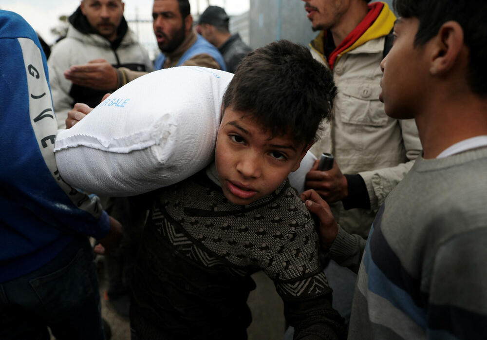 Palestinci u Rafi nose vreće brašna koje je podijelila UNRWA