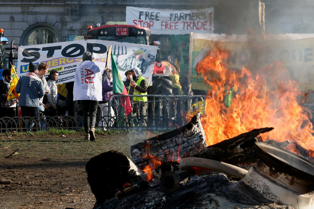 Zapaljeni predmeti gore dok se ljudi okupljaju pored traktora i transparenata tokom protesta belgijskih farmera u blizini Evropskog parlamenta na dan samita EU u Briselu, Belgija, Foto: reuters