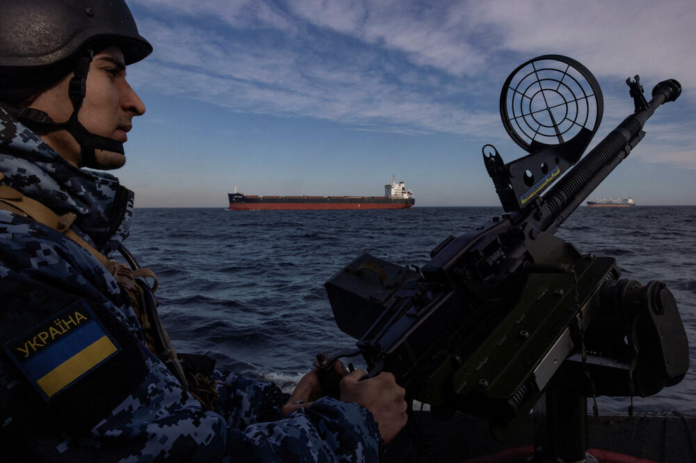 Pripadnik ukrajinske obalske straže drži pištolj na patrolnom čamcu dok teretni brod prolazi Crnim morem, usred napada Rusije na Ukrajinu, Foto: Reuters