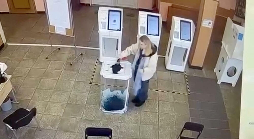 A woman pours paint into a ballot box at a polling station in Moscow
