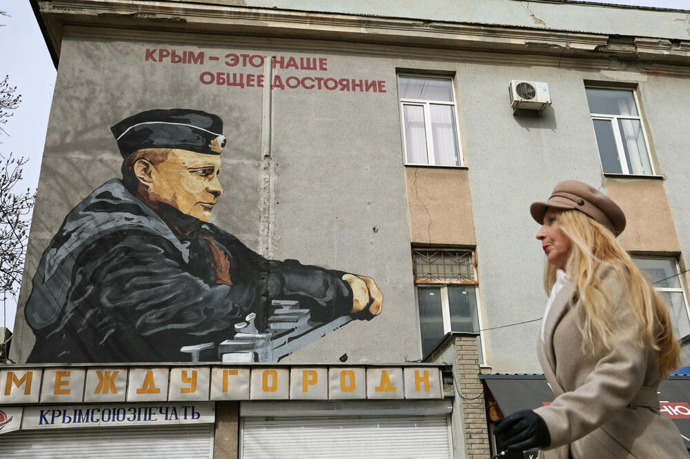 A woman walks past a mural of Russian President Vladimir Putin: Detail from Simferopol, a city in Crimea, Photo: Reuters