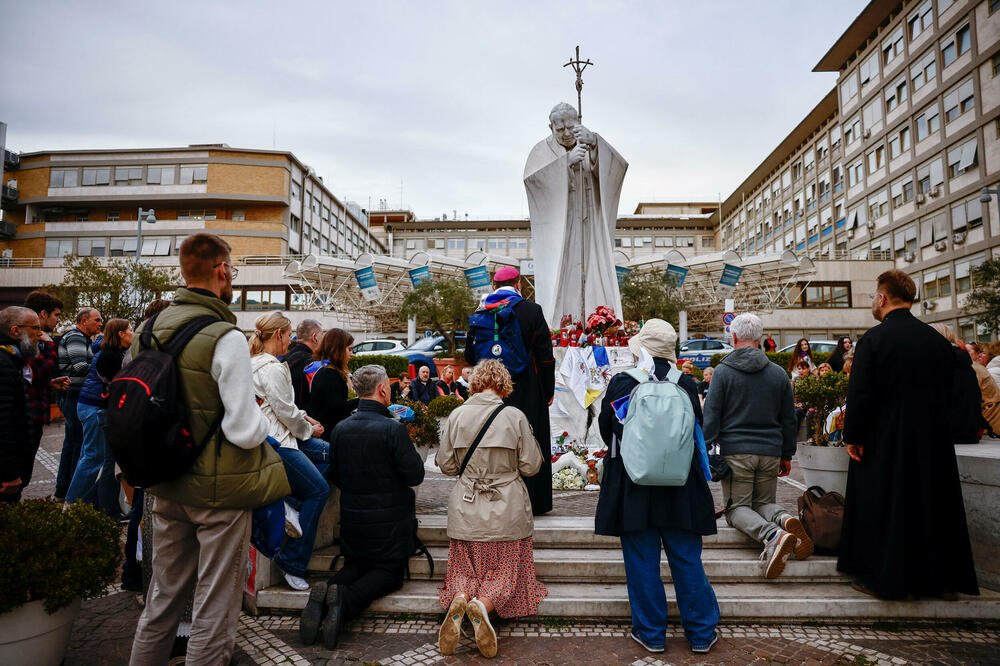 Ljudi se mole u blizini statue pokojnog pape Jovana Pavla II ispred bolnice u kojoj je papa Franjo primljen na liječenje, Foto: Reuters