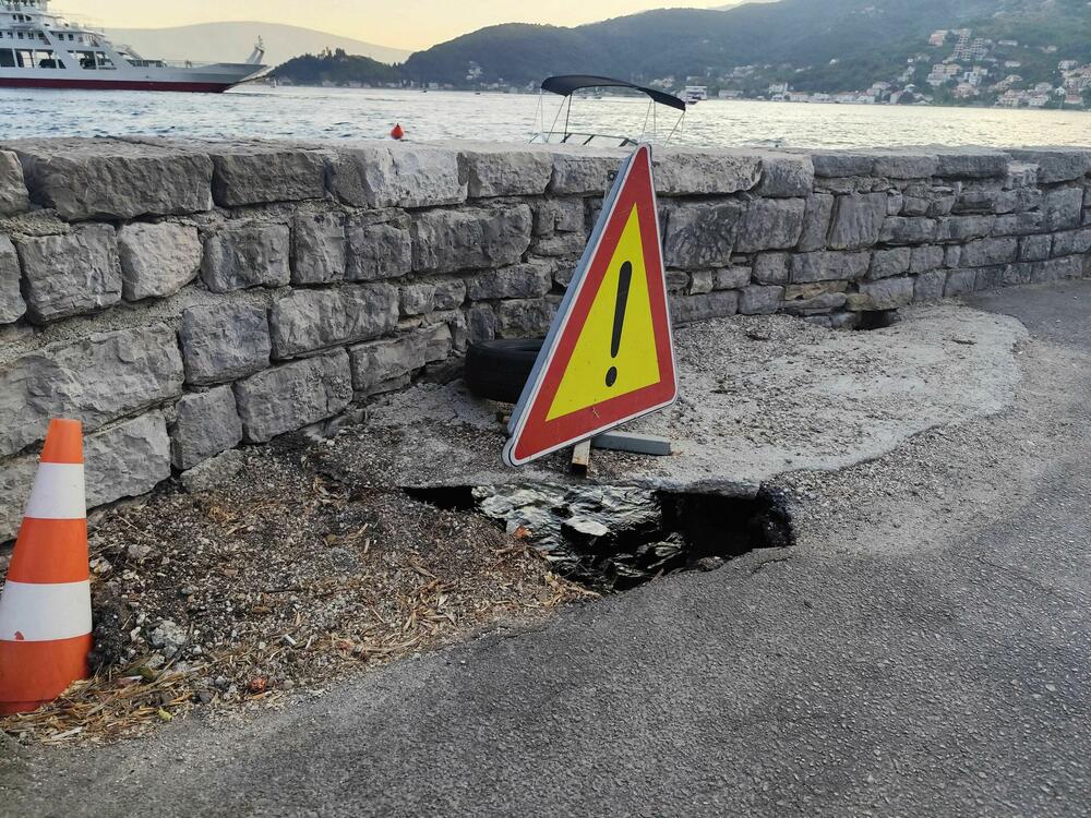 Rupa u kolovozu kroz koju se vidi more i razvaljeni potporni zid u Lepetanima