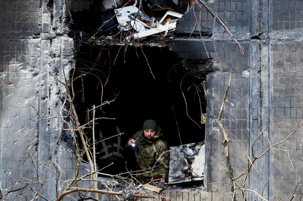 Istražilac gleda kroz prozor stambene zgrade oštećene tokom noćnog ruskog napada dronovima i projektilima: Kijev, Ukrajina, 14. novembar 2025., Foto: Reuters