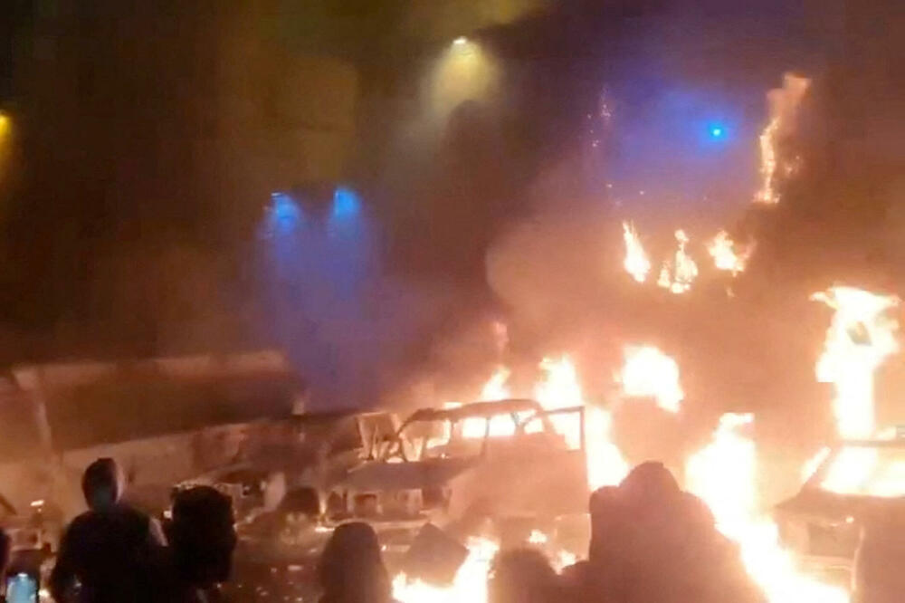 Demonstranti pored vozila u plamenu u Teheranu, Foto: REUTERS