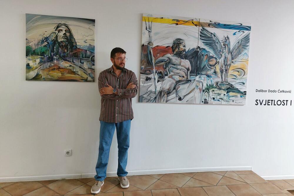 Ćetković na jednoj od izložbi i radovi &ldquo;Šapat neba&rdquo; i &ldquo;Otac i sin&rdquo; u pozadini, Foto: Privatna arhiva