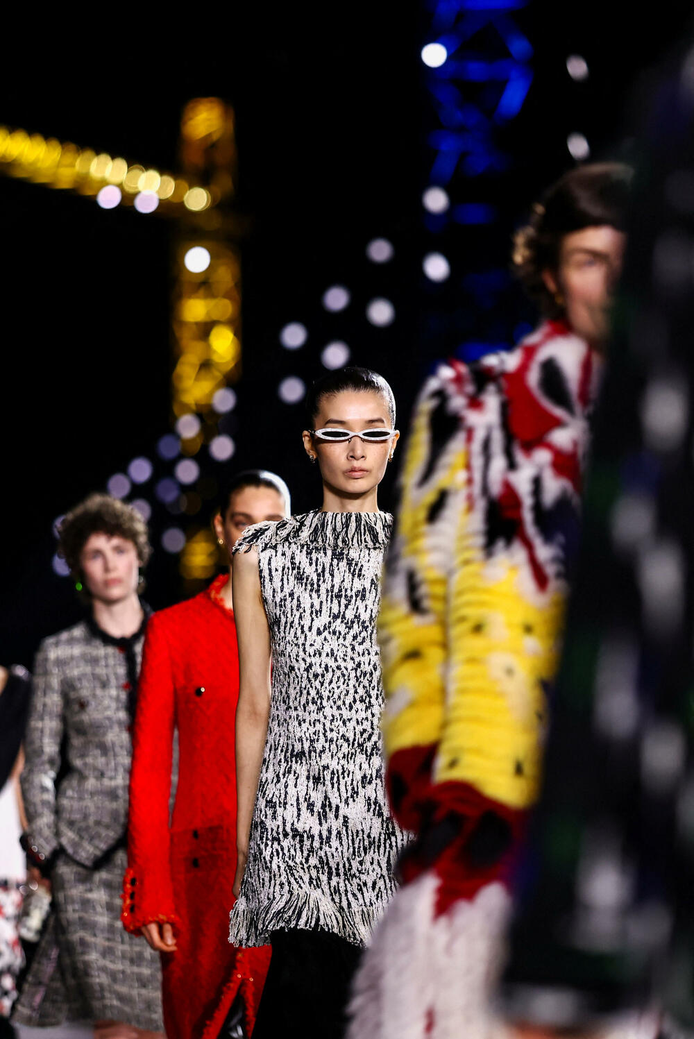 <p>Kostimi su bili kombinovani sa neuvučenim košuljama u kontrastnim dezenima i bojama, te upareni sa klasičnim Šanelovim dvobojnim salonkama u upadljivim kontrastima poput crvene i prelivajuće lila nijanse</p>