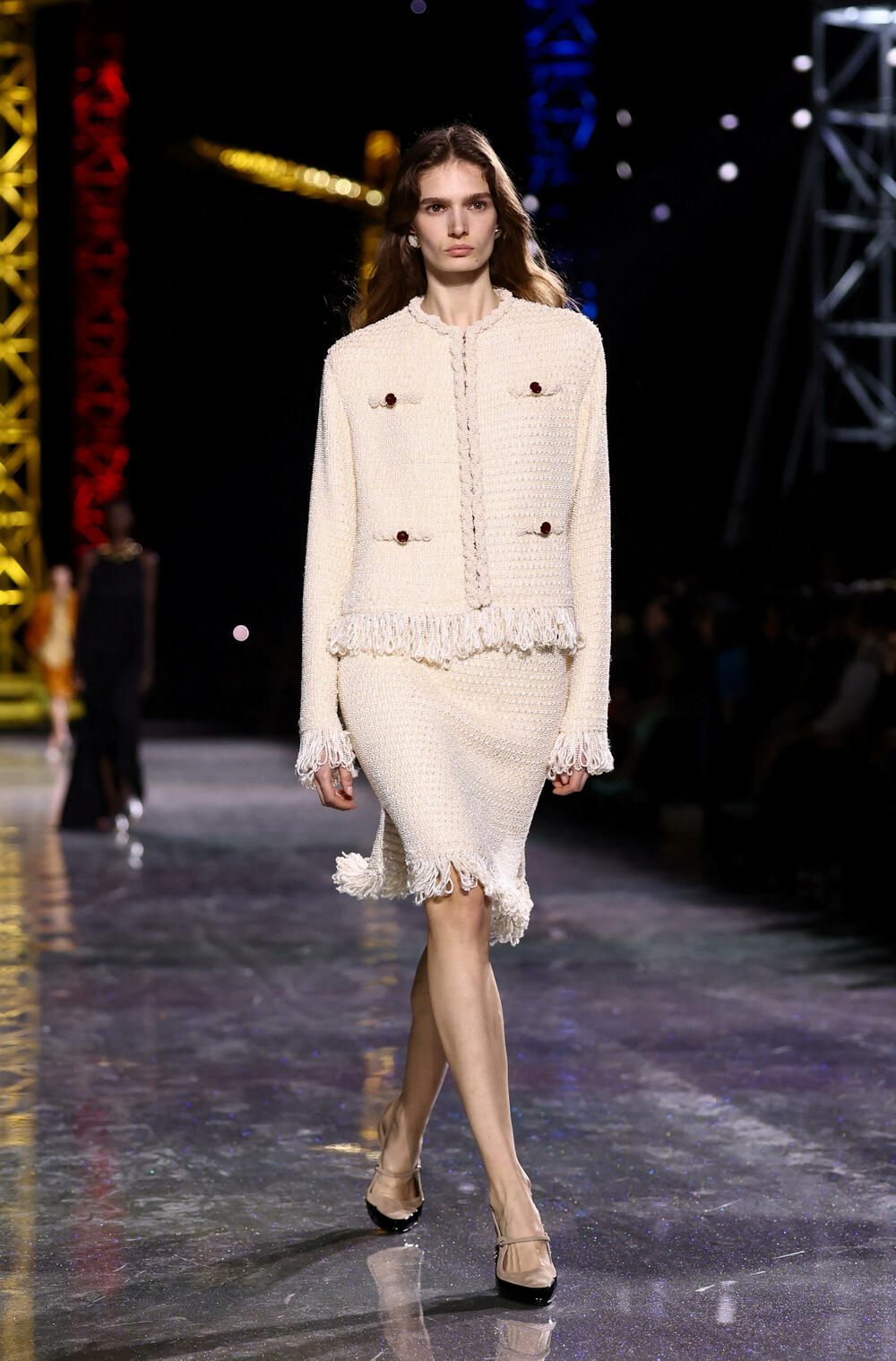 <p>Kostimi su bili kombinovani sa neuvučenim košuljama u kontrastnim dezenima i bojama, te upareni sa klasičnim Šanelovim dvobojnim salonkama u upadljivim kontrastima poput crvene i prelivajuće lila nijanse</p>