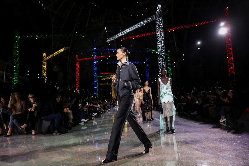 <p>Kostimi su bili kombinovani sa neuvučenim košuljama u kontrastnim dezenima i bojama, te upareni sa klasičnim Šanelovim dvobojnim salonkama u upadljivim kontrastima poput crvene i prelivajuće lila nijanse</p>