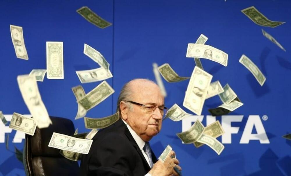 Blater u oblaku lažnih dolara koje je na njega bacio britanski komičar tokom konferencije za novinare u sjedištu FIFA u Cirihu 20. jula 2015. godine.