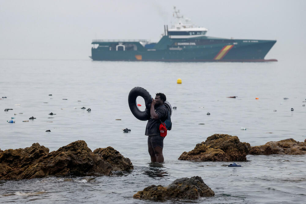 Migrant u moru kod Seute, dok u pozadini stoji španska Civilna garda 
