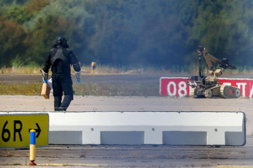 Policajac u zaštitnoj opremi prolazi pored robota za deaktiviranje eksplozivnih naprava (EOD) na aerodromu Lajpcig/Hale, Foto: Reuters