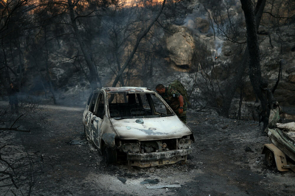 Muškarac posmatra izgorjeli automobil tokom požara u oblasti Peristerija na ostrvu Salamina, u blizini Atine, u Grčkoj, Foto: Reuters