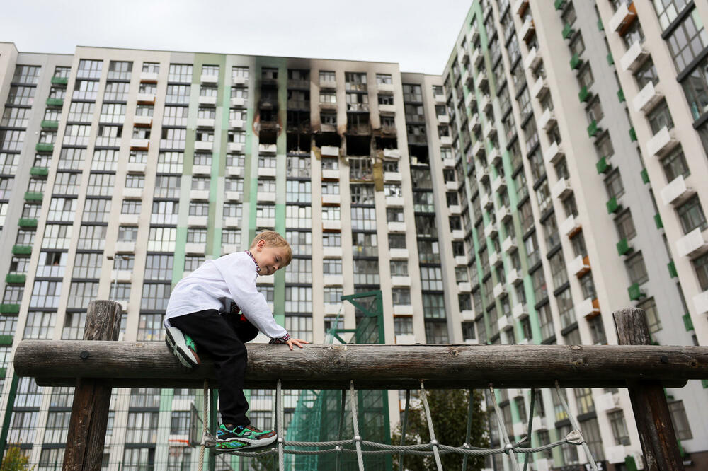 Šestogodišnji Svjatoslav, koji je juče krenuo u prvi razred, ispred oštećene zgrade u Kijevu, Foto: REUTERS